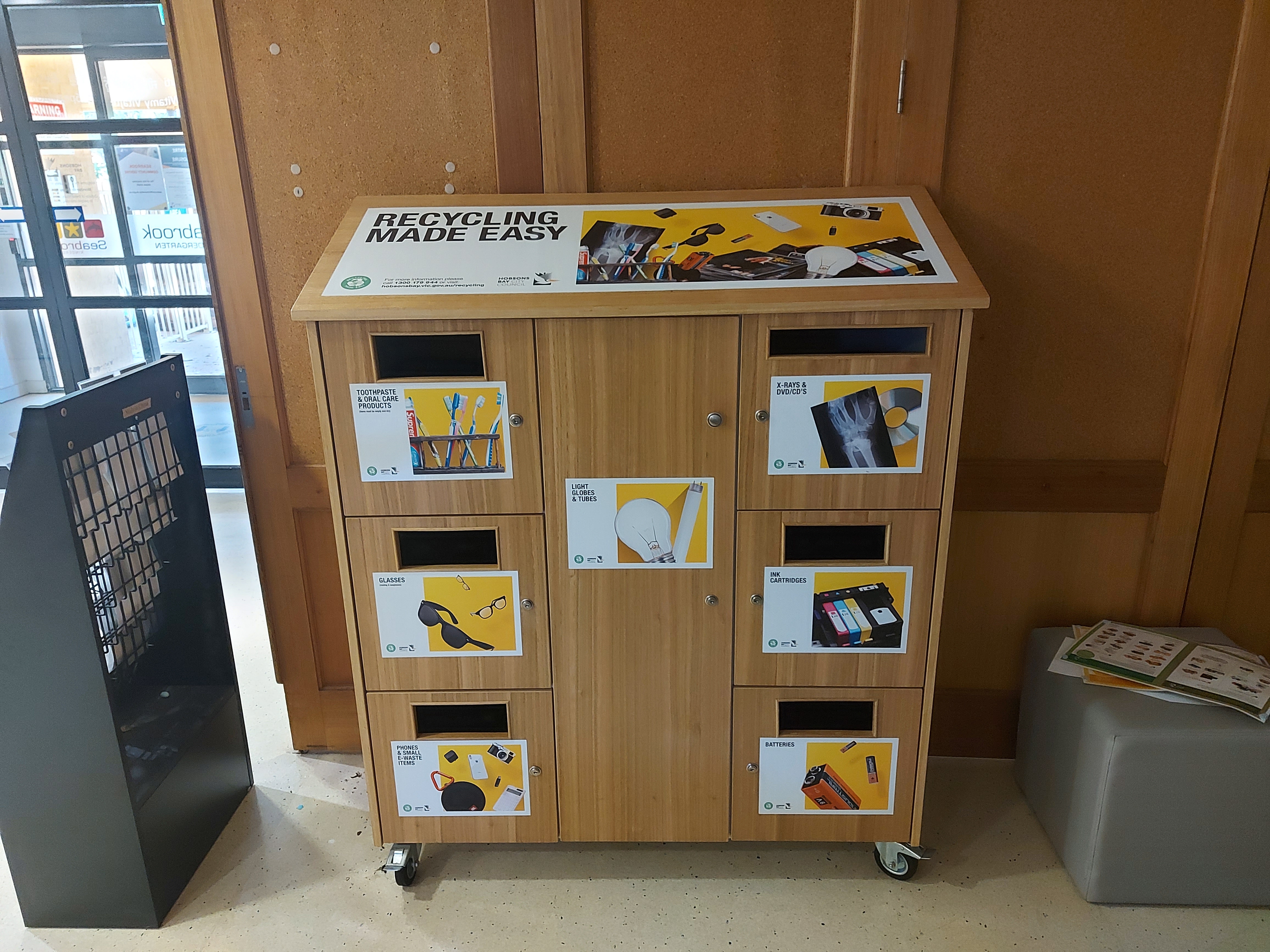 Recycling Made Easy hub stationed at local community centre. Cabinet with sections for different items such as sunglasses, light globes and batteries.