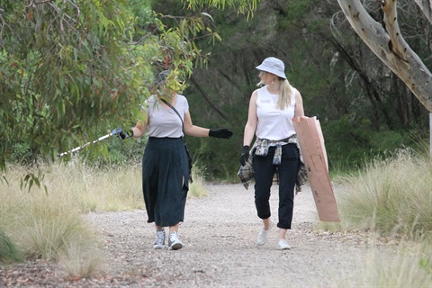 Two community members picking up rubbish together in a park
